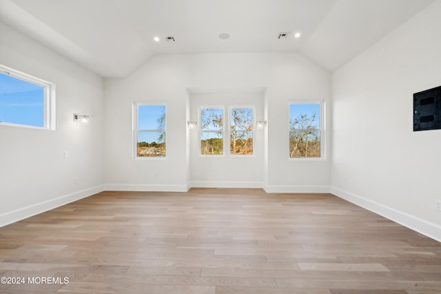 spare room with lofted ceiling and light wood-type flooring