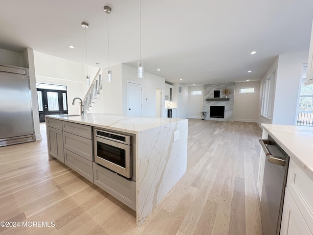 kitchen with decorative light fixtures, light stone counters, a spacious island, and a healthy amount of sunlight