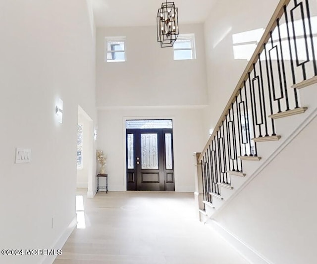 foyer with hardwood / wood-style floors, a towering ceiling, and an inviting chandelier