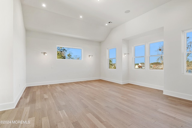 spare room featuring light wood-type flooring, a wealth of natural light, and lofted ceiling