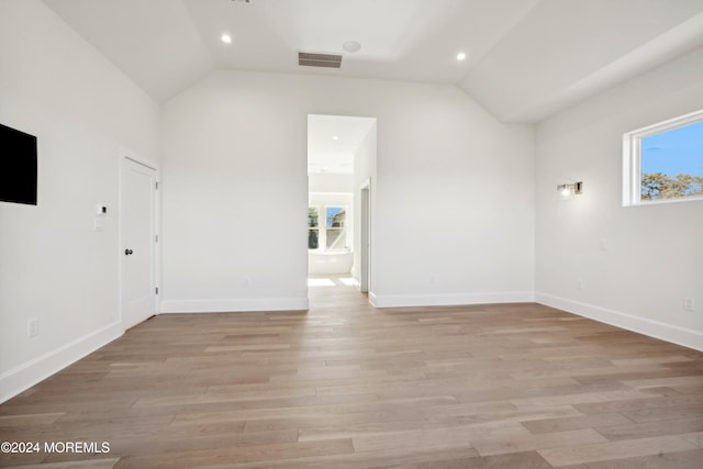 spare room with light hardwood / wood-style flooring and vaulted ceiling