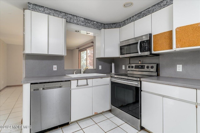 kitchen featuring white cabinets, sink, light tile patterned floors, and stainless steel appliances