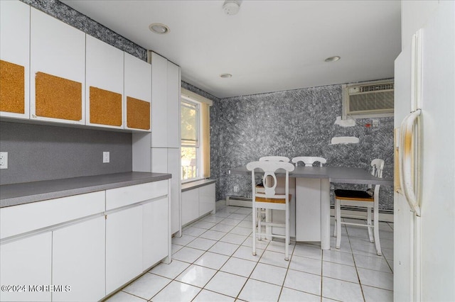 kitchen with white cabinetry, a wall unit AC, white fridge, and a baseboard heating unit