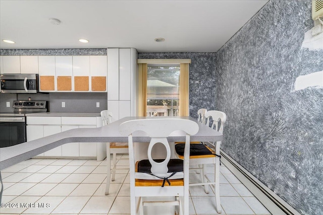 kitchen featuring stainless steel appliances, white cabinetry, baseboard heating, a breakfast bar area, and light tile patterned floors