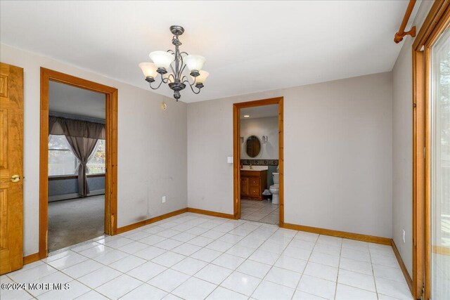 unfurnished room with a chandelier and light tile patterned floors