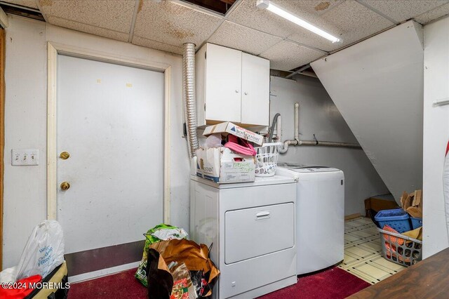 clothes washing area featuring cabinets and washing machine and clothes dryer