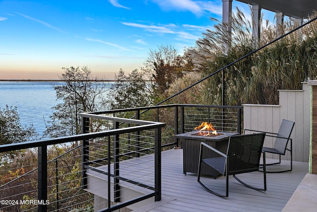 deck at dusk with a water view and a fire pit