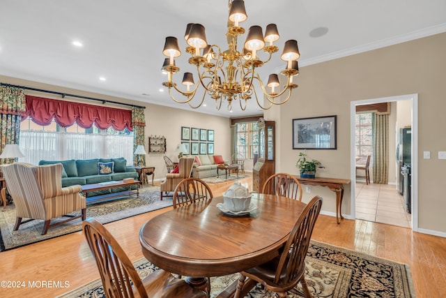 dining space with ornamental molding, light wood-type flooring, and a notable chandelier