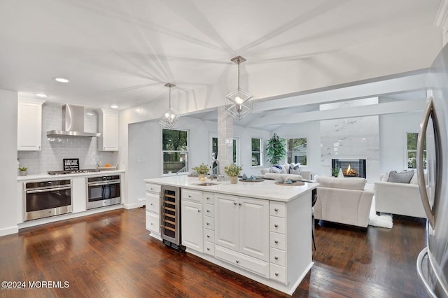 kitchen with white cabinetry, appliances with stainless steel finishes, pendant lighting, beverage cooler, and wall chimney exhaust hood