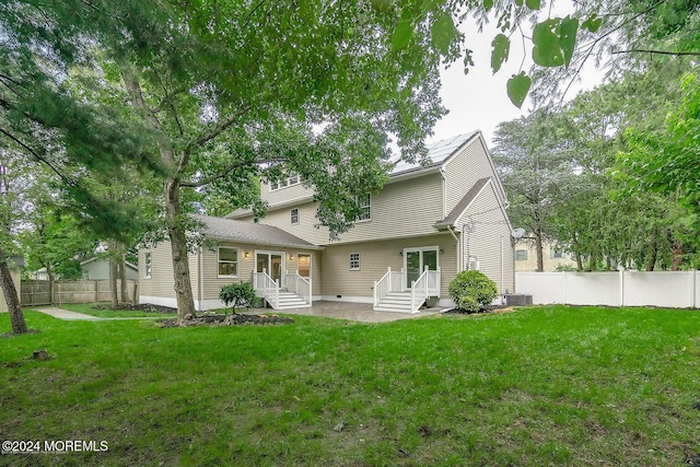 rear view of property featuring central air condition unit and a lawn