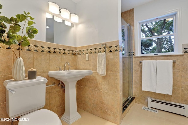 bathroom featuring a shower with door, tile patterned floors, a baseboard radiator, toilet, and tile walls