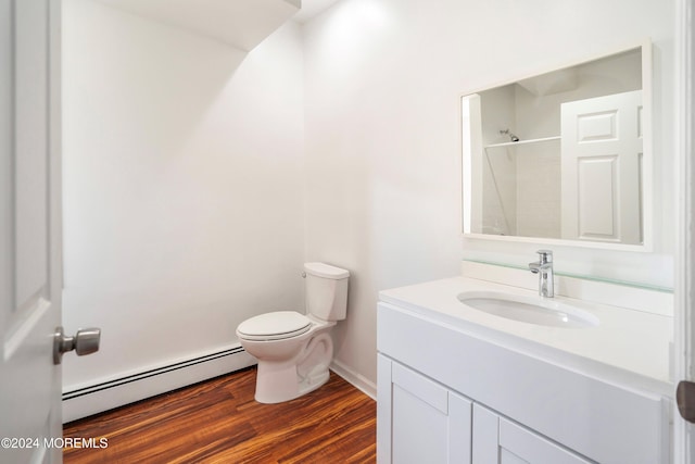 bathroom with toilet, hardwood / wood-style floors, baseboard heating, vanity, and a shower