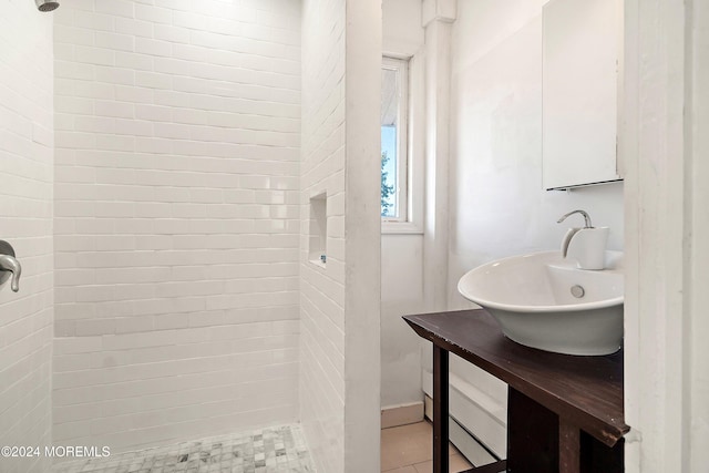 bathroom with tile patterned flooring, tiled shower, and sink