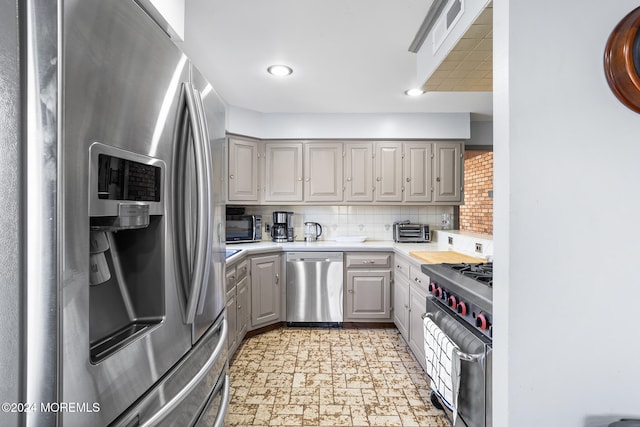 kitchen featuring gray cabinets, decorative backsplash, and stainless steel appliances