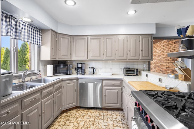 kitchen featuring gray cabinetry, backsplash, sink, and stainless steel appliances