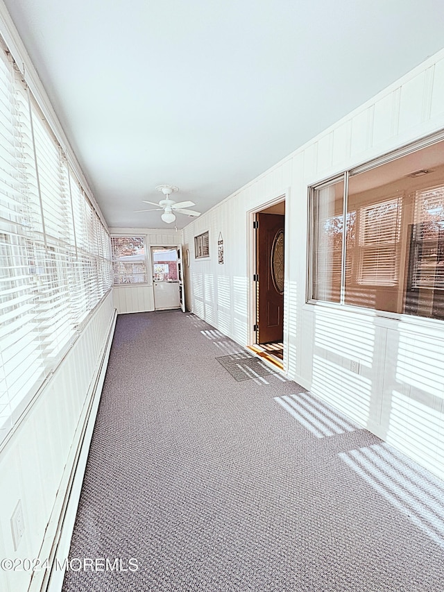 unfurnished sunroom featuring ceiling fan and baseboard heating