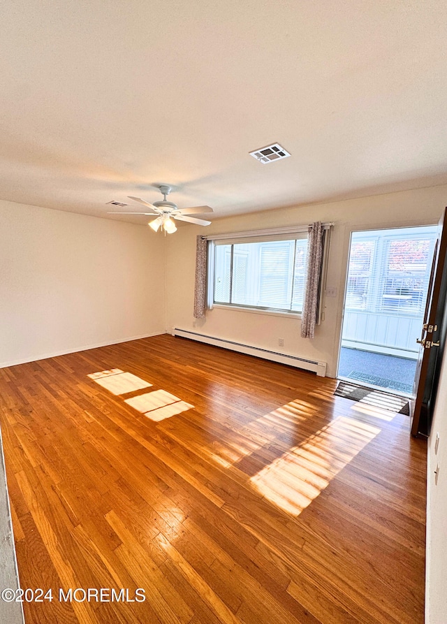 unfurnished room featuring hardwood / wood-style floors, a baseboard radiator, and ceiling fan