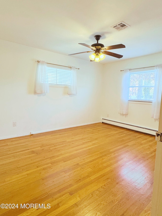 spare room with a baseboard heating unit, light hardwood / wood-style floors, and ceiling fan