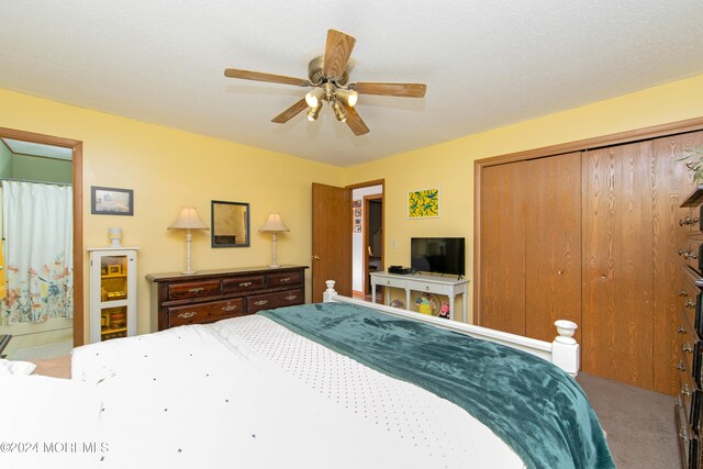 carpeted bedroom with ceiling fan, a textured ceiling, and a closet