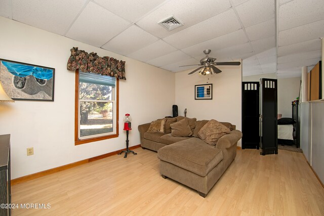 living room featuring a drop ceiling, hardwood / wood-style floors, and ceiling fan