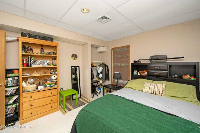 carpeted bedroom featuring a paneled ceiling and a closet