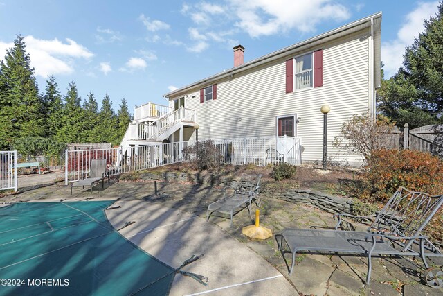 rear view of property with a covered pool and a patio area