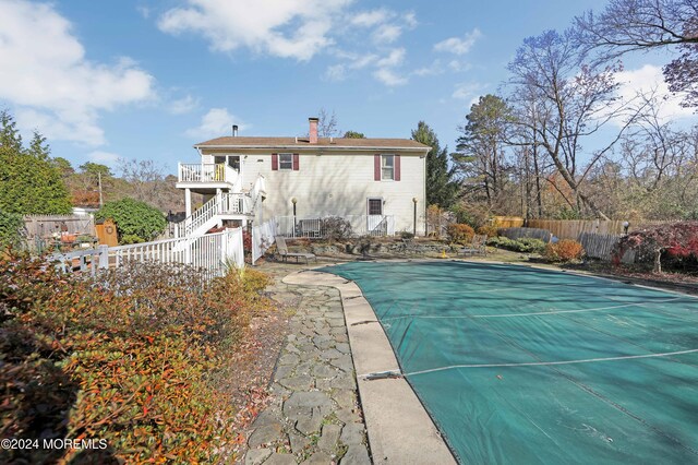 rear view of house featuring a covered pool