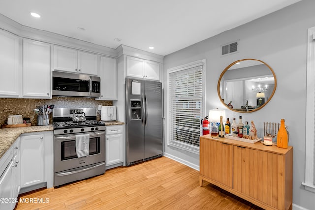 kitchen with light stone countertops, appliances with stainless steel finishes, backsplash, light hardwood / wood-style flooring, and white cabinetry