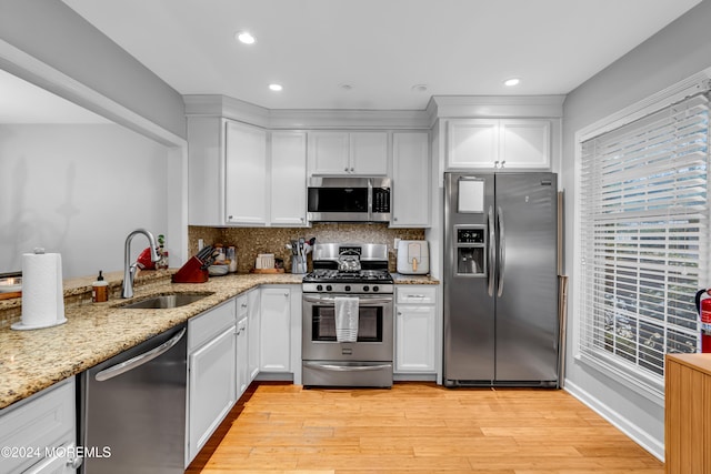 kitchen with white cabinetry, sink, stainless steel appliances, and light hardwood / wood-style floors