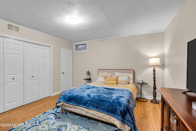 bedroom with a closet, ornamental molding, and hardwood / wood-style flooring