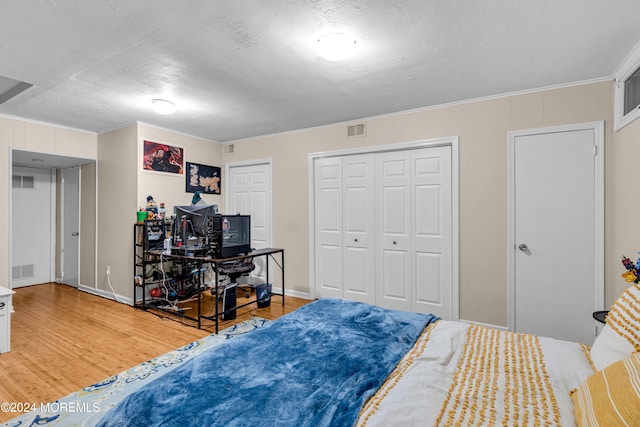 bedroom with multiple closets, ornamental molding, and hardwood / wood-style flooring