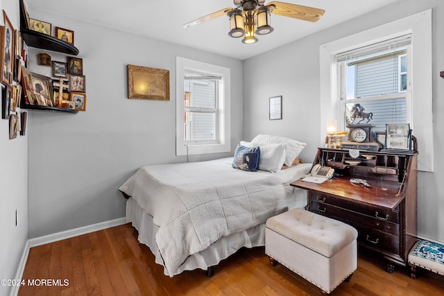 bedroom with ceiling fan, wood-type flooring, and multiple windows