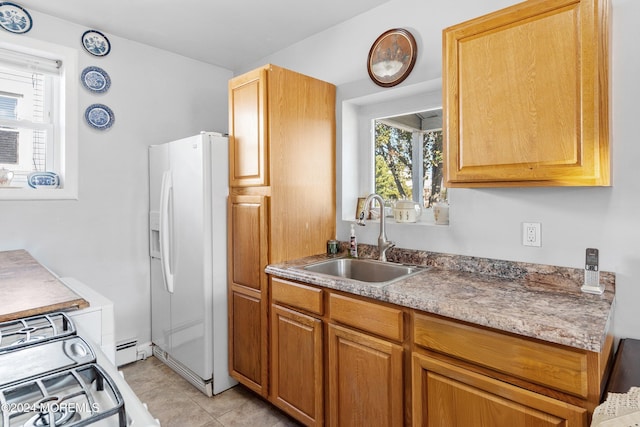 kitchen with sink, light tile patterned floors, baseboard heating, range with gas stovetop, and white fridge with ice dispenser