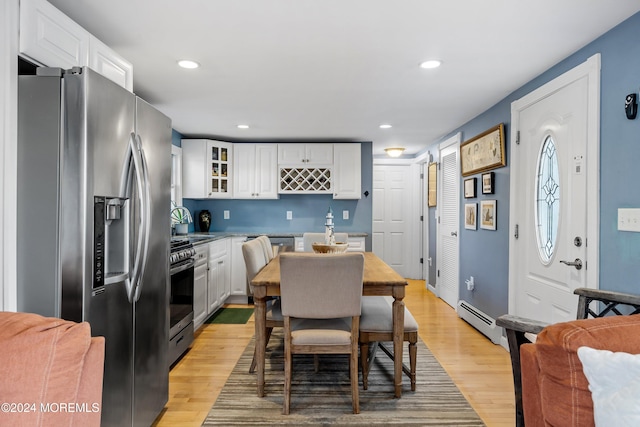 kitchen featuring sink, white cabinetry, light wood-type flooring, stainless steel appliances, and a baseboard heating unit