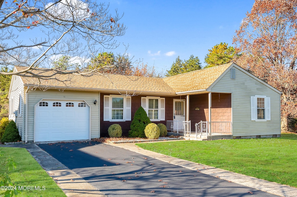 ranch-style house featuring covered porch, a garage, and a front lawn