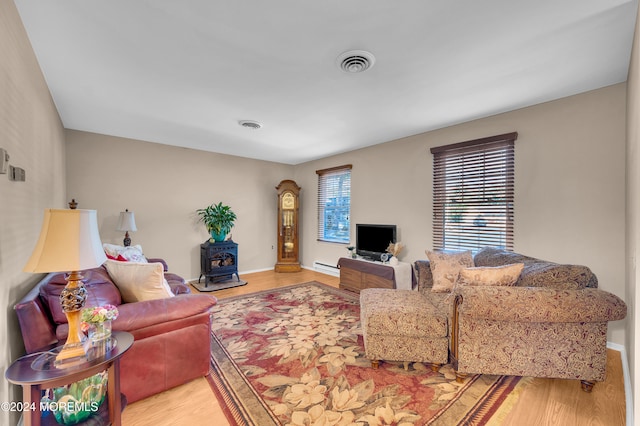 living room with hardwood / wood-style floors, a wood stove, and a baseboard heating unit