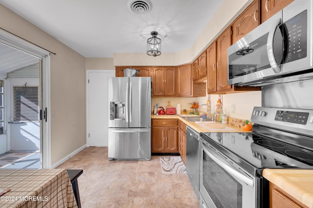 kitchen featuring sink, an inviting chandelier, decorative light fixtures, and stainless steel appliances