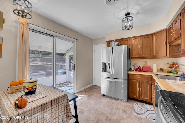 kitchen featuring stainless steel appliances, decorative light fixtures, a notable chandelier, decorative backsplash, and sink