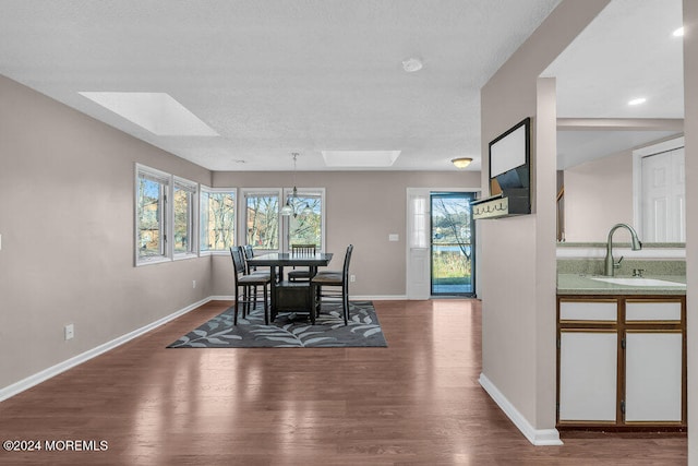 dining area featuring hardwood / wood-style floors, a wealth of natural light, a textured ceiling, and a skylight