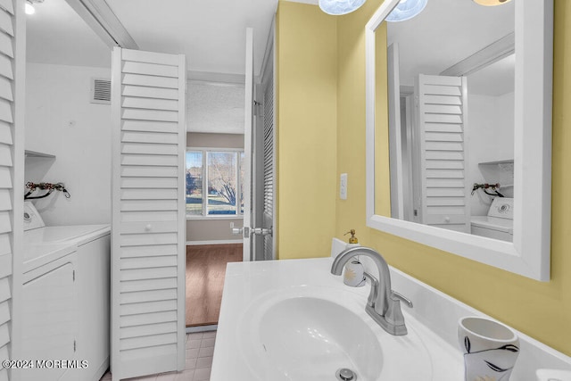 bathroom featuring washing machine and clothes dryer, tile patterned flooring, and vanity