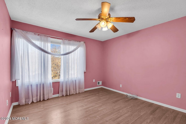 empty room featuring a textured ceiling, light wood-type flooring, and ceiling fan