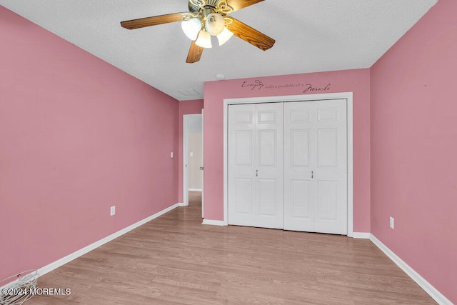 unfurnished bedroom featuring a textured ceiling, light wood-type flooring, ceiling fan, and a closet