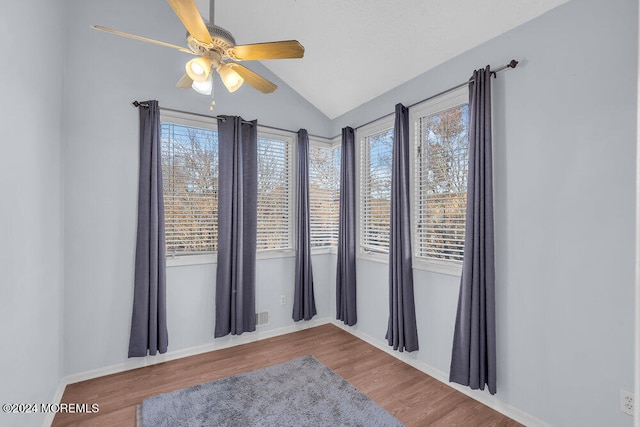 unfurnished room featuring ceiling fan, vaulted ceiling, hardwood / wood-style flooring, and a healthy amount of sunlight