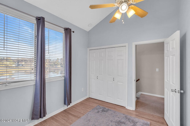 bedroom with ceiling fan, a closet, light wood-type flooring, and vaulted ceiling