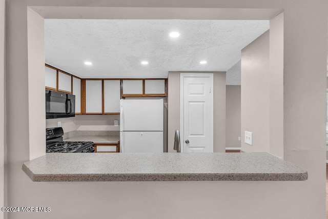 kitchen with black appliances, kitchen peninsula, and a textured ceiling