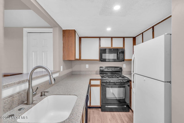 kitchen with black appliances, white cabinetry, light wood-type flooring, a textured ceiling, and sink