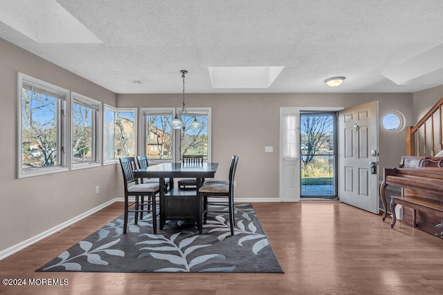 dining space featuring dark hardwood / wood-style floors, a textured ceiling, a chandelier, and a skylight