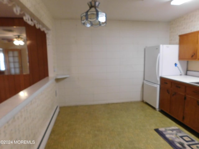 kitchen featuring hanging light fixtures, ceiling fan, white refrigerator, and a baseboard heating unit