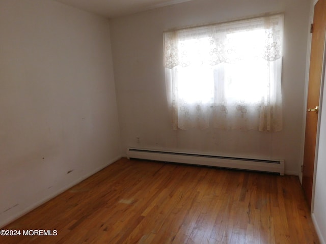 empty room featuring baseboard heating and light hardwood / wood-style flooring