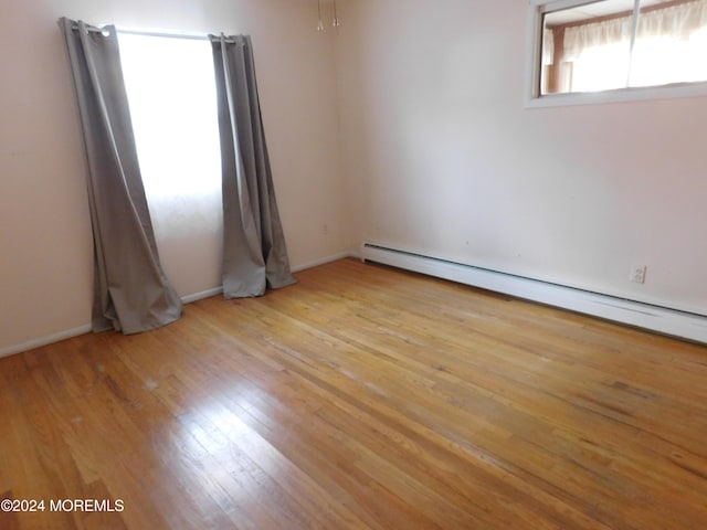 spare room featuring a baseboard heating unit and light wood-type flooring